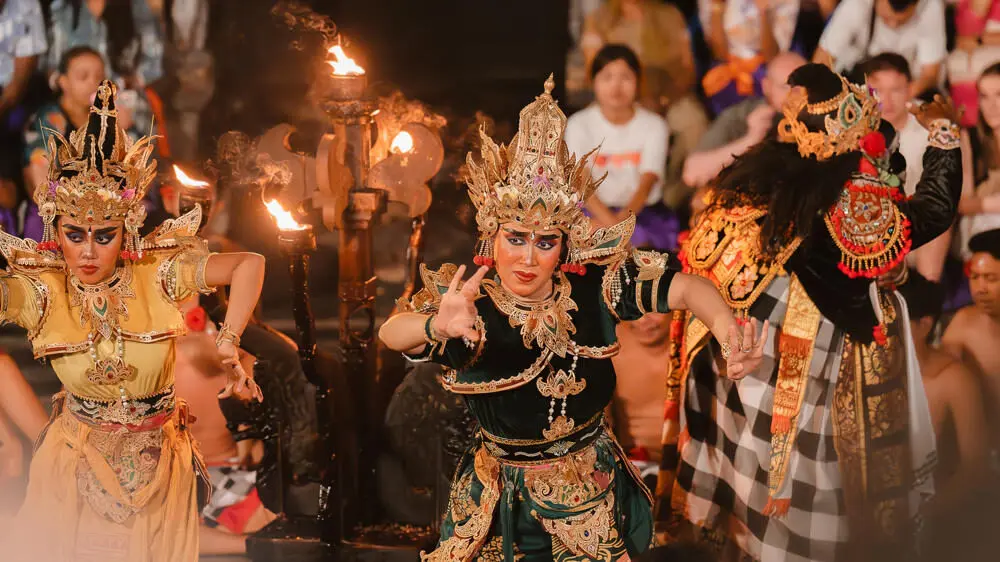Performers in ornate traditional costumes during a Kecak fire dance, one of Bali's most unique night experiences, illuminated by flaming torches.