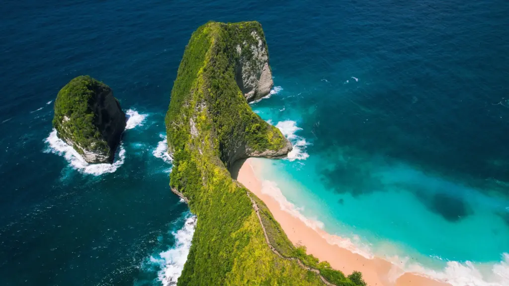 Aerial view of Kelingking Beach Nusa Penida with the T-Rex shaped cliff, turquoise ocean, and secluded white sand shoreline
