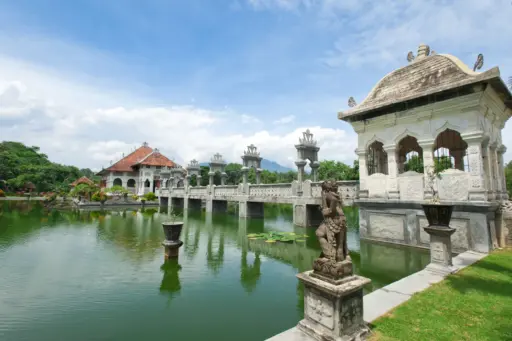 Historic Puri Agung Karangasem water palace near Seraya Bali with stone bridge, statues, and reflections on the pond