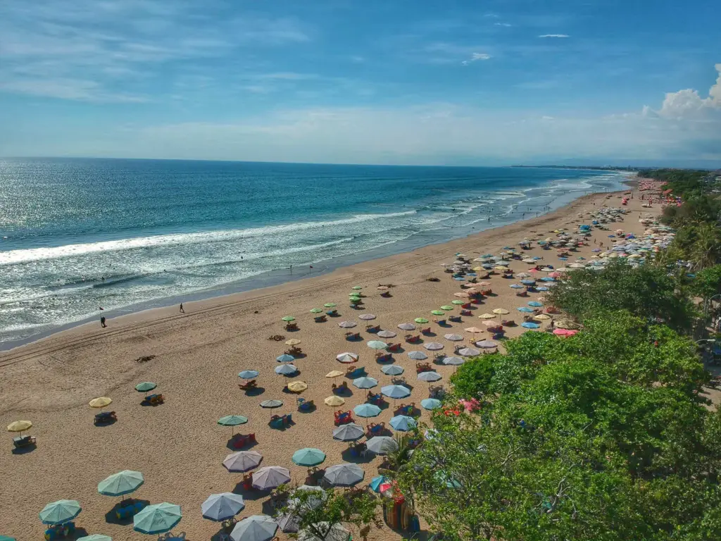 Seminyak Beach Bali with colorful umbrellas, golden sand, and waves perfect for surfing