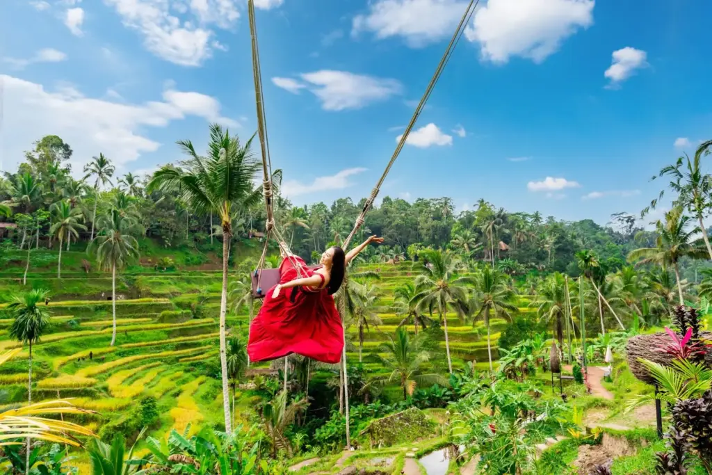 Woman on a swing with panoramic views of Bali rice terraces in Tegallalang