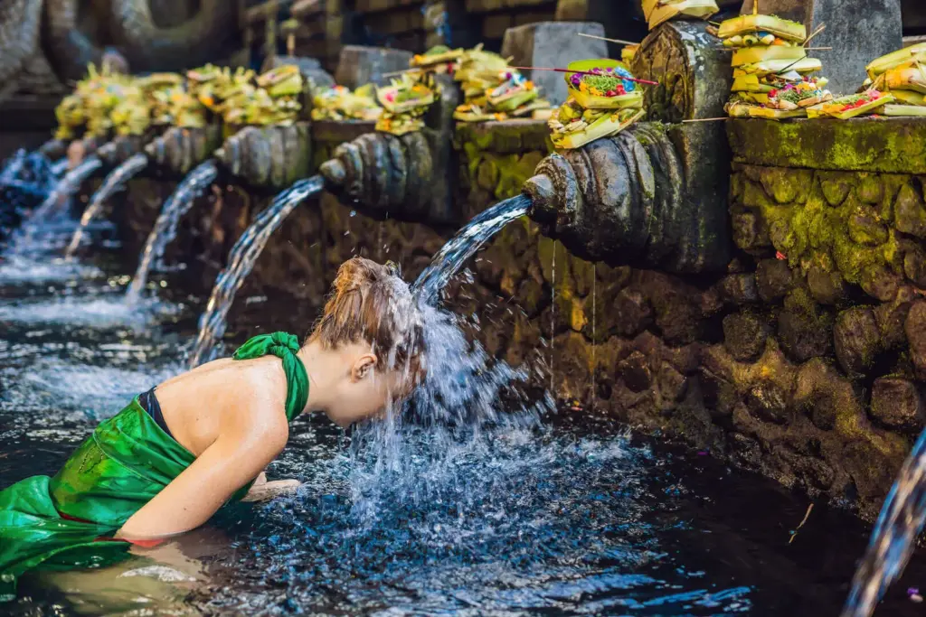Woman participating in a purification ritual at Bali’s holy spring water temple, symbolizing the spiritual tourism dilemma in Bali